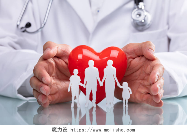 医生的手保护红色心脏与家庭医生的手保护红色心脏与家庭数字在反射书桌上